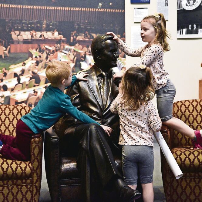 Símbolo. Niños estadounidenses tocan una estatua de George H. W. Bush, dentro de la biblioteca del mismo nombre en College Station, Texas. Foto: SERGIO FLORES. REUTERS