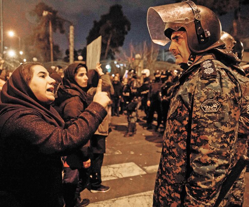 Una mujer encara a un policía iraní en Teherán, durante la vigilia con velas en memoria de las víctimas del Boeing 737 de Ukraine International Airlines, que derribó Teherán por “error ”. Foto: MONA HOOBEHFEKR. AFP