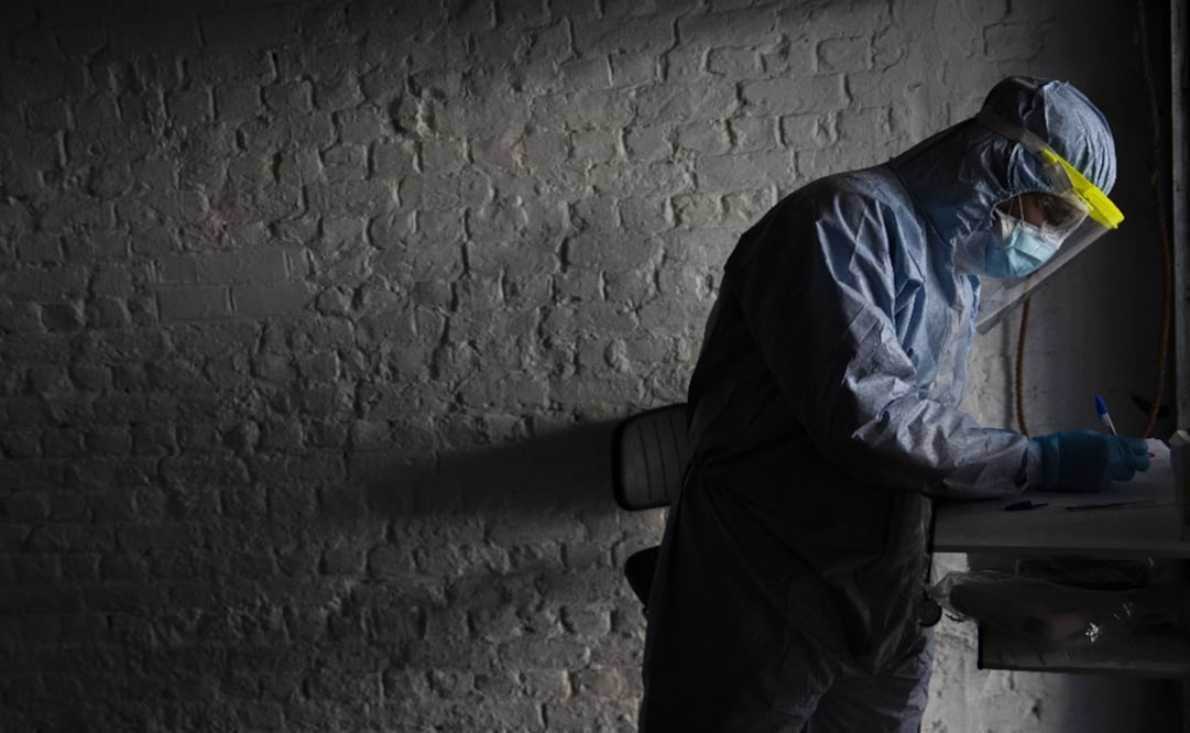 A doctor, wearing full protective equipment, takes notes as he screens a patient with symptoms of coronavirus - Photo: Francisco Seco/AP