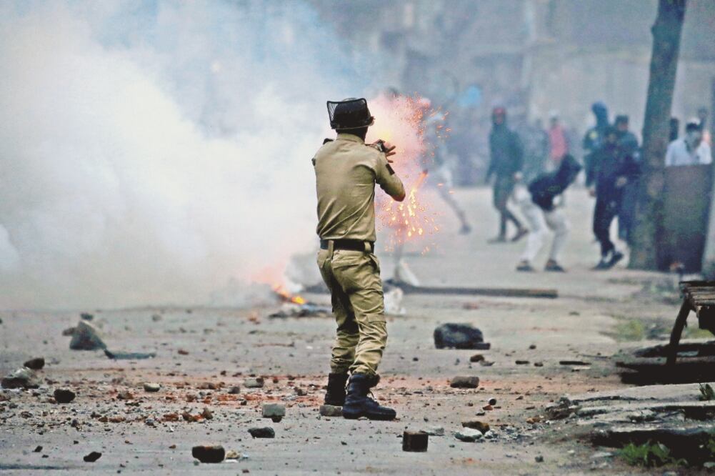 Un policía indio dispara un proyectil de gas lacrimógeno contra los manifestantes, ayer durante una protesta contra los recientes asesinatos en Cachemira, un territorio disputado por India y Paquistán. (DANISH ISMAIL. REUTERS)