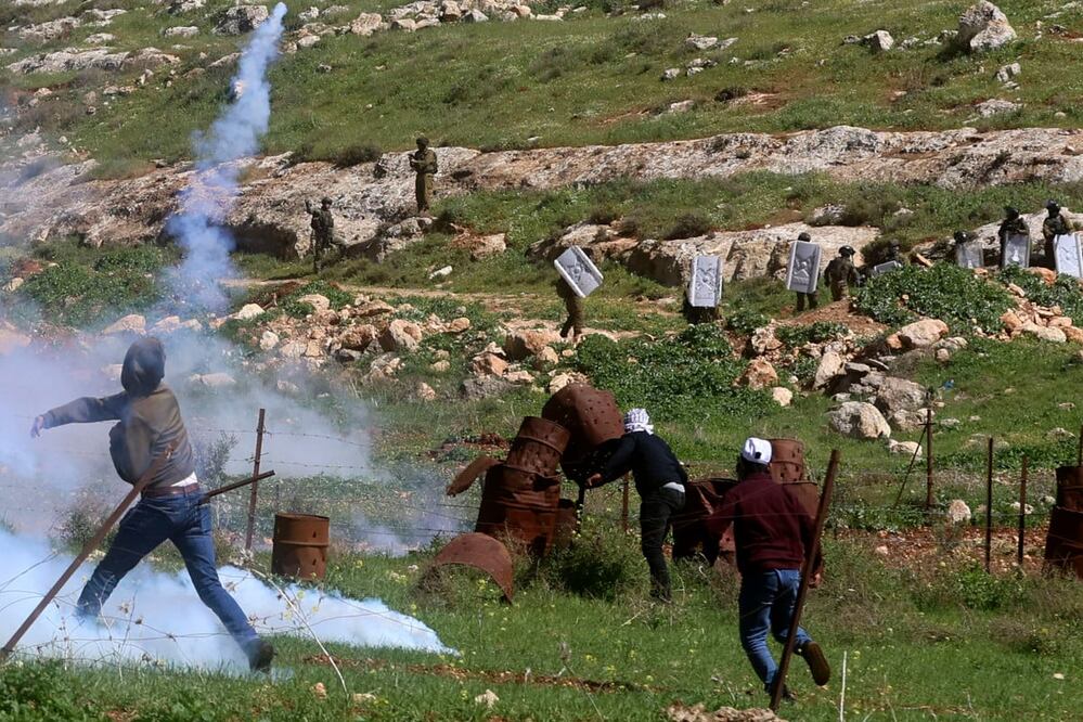Un manifestante palestino arroja un bote de gas lacrimógeno a los soldados israelíes, en Cisjordania. Foto: AFP