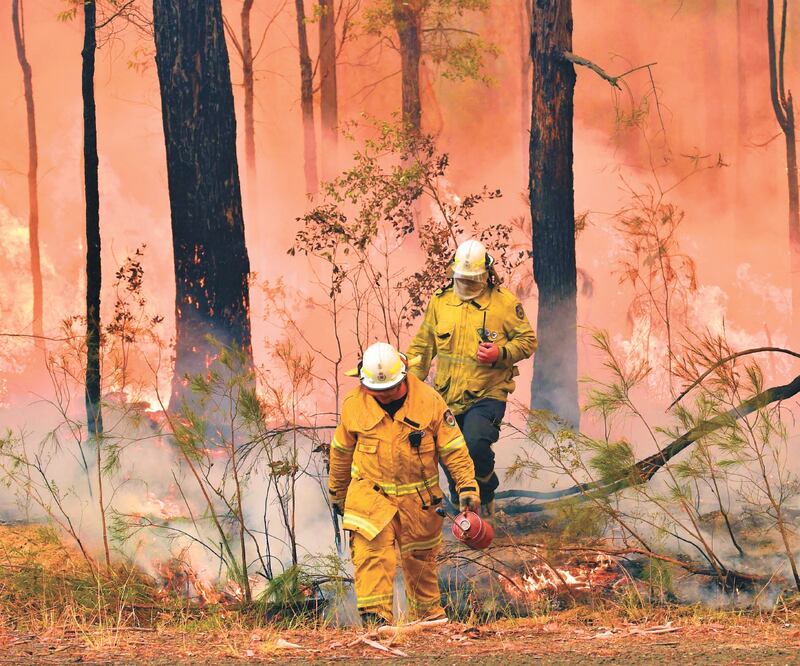 Bomberos combaten el fuego en Jerrawangala, mientras otros buscan rescatar a personas atrapadas. Foto: PETER PARKS. AFP