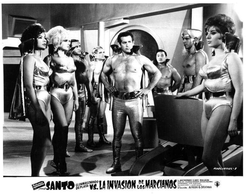 El cine de luchadores también tuvo sus películas con temática espacial, “El santo contra la invasión de los marcianos” es uno de los ejemplos más populares. La película ofrece una versión de extraterrestres con trajes brillantes y exóticos que enfrentan al enmascarado de plata. Foto: Especial.