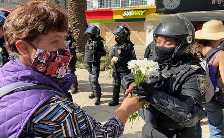 Mujeres policías reciben flores de manifestantes durante marcha del 8M 