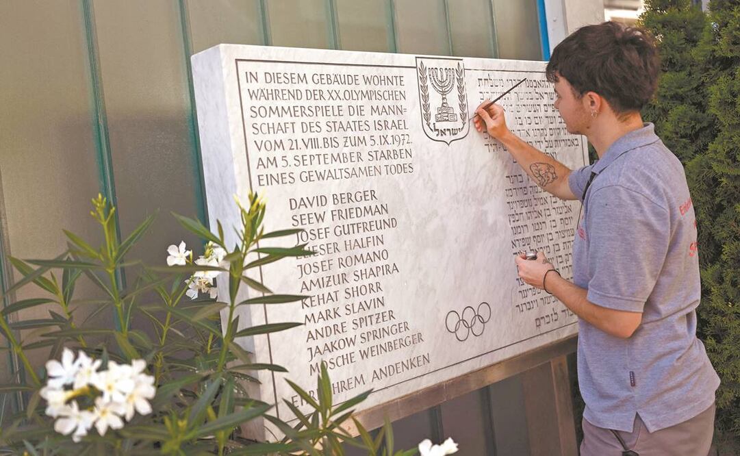 Un joven restaura la inscripción de una placa conmemorativa frente a un edificio de apartamentos en la antigua Villa Olímpica de Múnich, al sur de Alemania. Foto: Matthias Schrader/AP