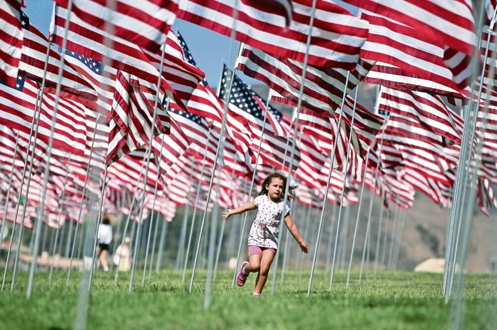 Una niña juega entre las banderas del memorial construido en Malibú, California, en honor a las casi 3 mil víctimas de los atentados ocurridos el 11 de septiembre de 2001, hecho del que ayer se cumplieron 15 años (LUCY NICHOLSON. REUTERS)