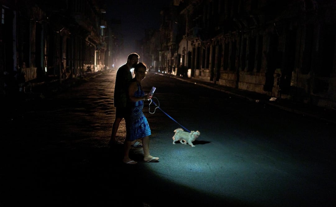 La gente enciende una linterna mientras cruza una calle con su perro durante un apagón en La Habana, el miércoles 10 de septiembre de 2025. Foto: AP