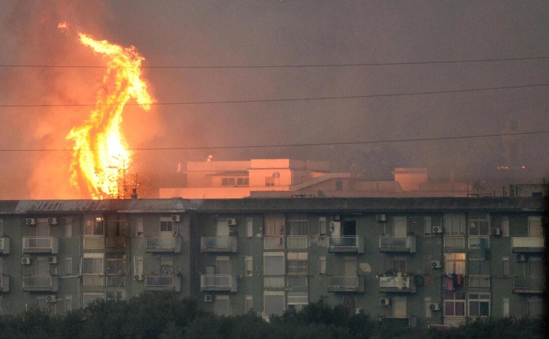 Una columna de fuego se eleva tras un bloque de viviendas en el área de Monte Grifone en la ciudad de Ciaculli, cerca de Palermo. Foto: EFE