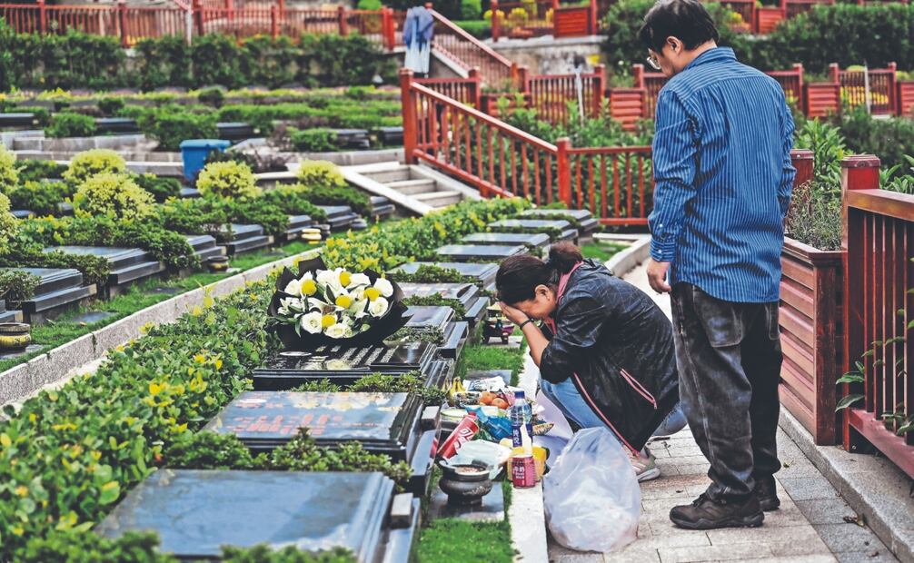 Seakoo Wu y su esposa, usuarios de un software de Inteligencia Artificial que recrea a su hijo fallecido, en su tumba. Foto: de AFP