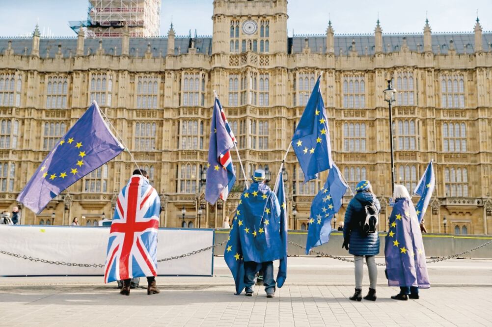 Proeuropeíestas sostienen banderas del bloque y de Reino Unido, durante una protesta realizada ayer contra el Brexit afuera del Parlamento británico, en Londres. (MATT DUNHAM. AP)