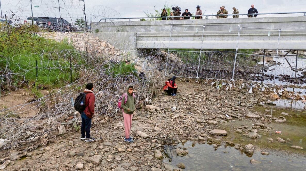 Soldados y agentes estadounidenses vigilan a un pequeño grupo de inmigrantes que cruzaron el río Bravo hacia EU, en Eagle Pass, Texas. Foto: de John Moore. AFP