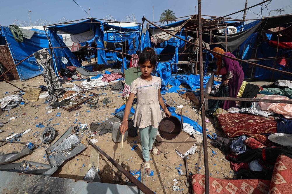 Palestinas buscan objetos rescatables en refugios destruidos tras los ataques aéreos israelíes nocturnos que, según informes, impactaron en tiendas de campaña para gazatíes desplazados frente al hospital de los Mártires de Al-Aqsa en Deir el-Balah, en el centro de la Franja de Gaza. Foto: AFP