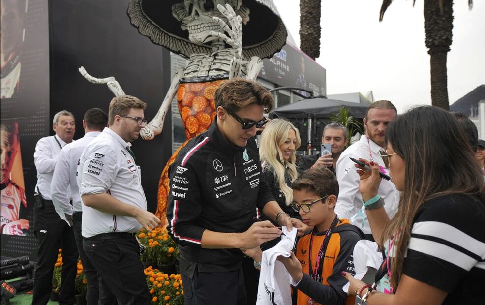 El piloto de Mercedes AMG Petronas, George Russell interactúa con fans rodeado de figuras alusivas al Día de Muertos. Foto: AP