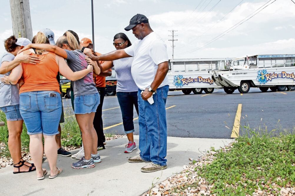 Personas rezan afuera de Ride the Ducks, compañía que es dueña del bote involucrado en el accidente en el lago Table Rock, en Missouri. Foto: CHARLIE RIEDEL. AP
