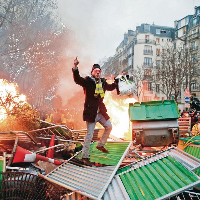 Un manifestante hace un gesto en una barricada en llamas, en París, durante una protesta antigubernamental convocada por los chalecos amarillos. ABDUL ABEISSA. AFP
