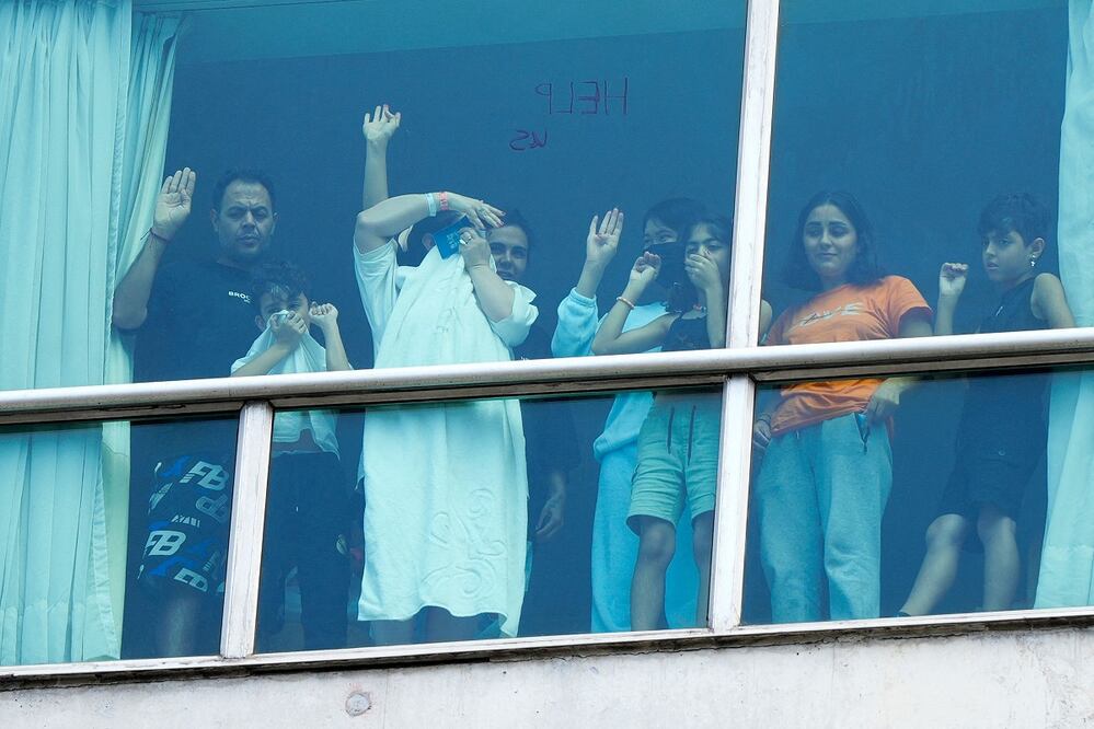 Migrantes deportados de Estados Unidos gesticulan mientras miran por la ventana del Hotel Decápolis donde se alojan temporalmente en Ciudad de Panamá. FOTO: ARNULFO FRANCO. AFP