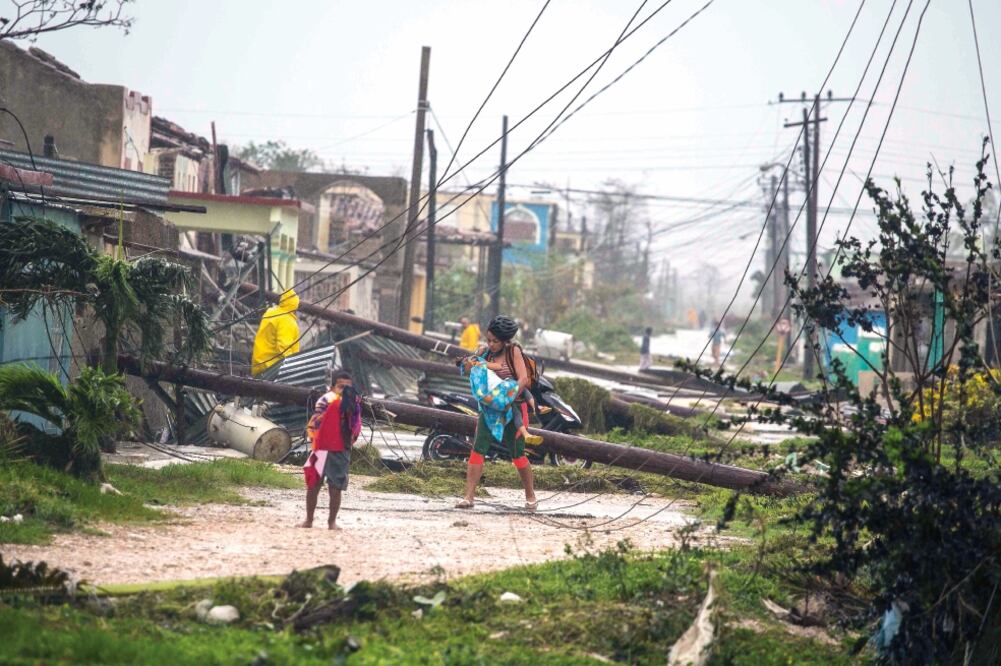 Una mujer y dos niños caminaban ayer entre postes derribados por el huracán Irma, en Caibarien, Cuba, donde no hubo reportes de muertos ni lesionados. (DESMOND BOYLAN. AP)