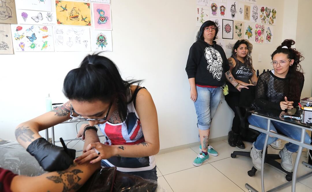 Minerva (front) tattoos an arm while in the background Katyte, Spooky Pony and Nemesis pose next to their sketches - Photo: Berenice Fregoso/EL UNIVERSAL