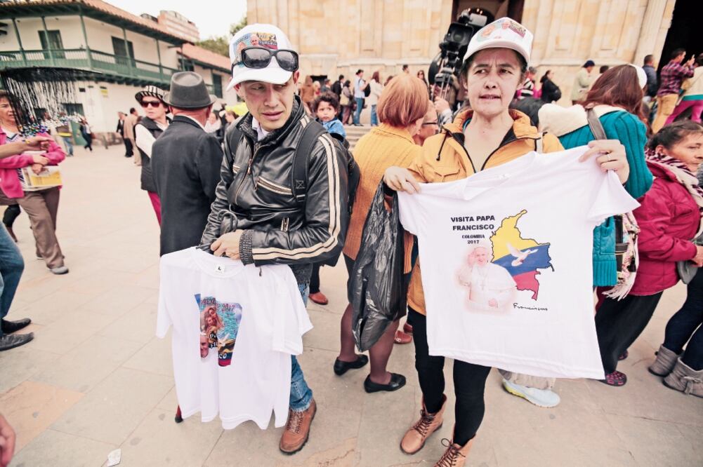 Dos personas ofrecen mercancía alusiva a la visita del papa Francisco, quien llega hoy a Colombia para una gira de cinco días. (JOSÉ JÁCOME. EFE)