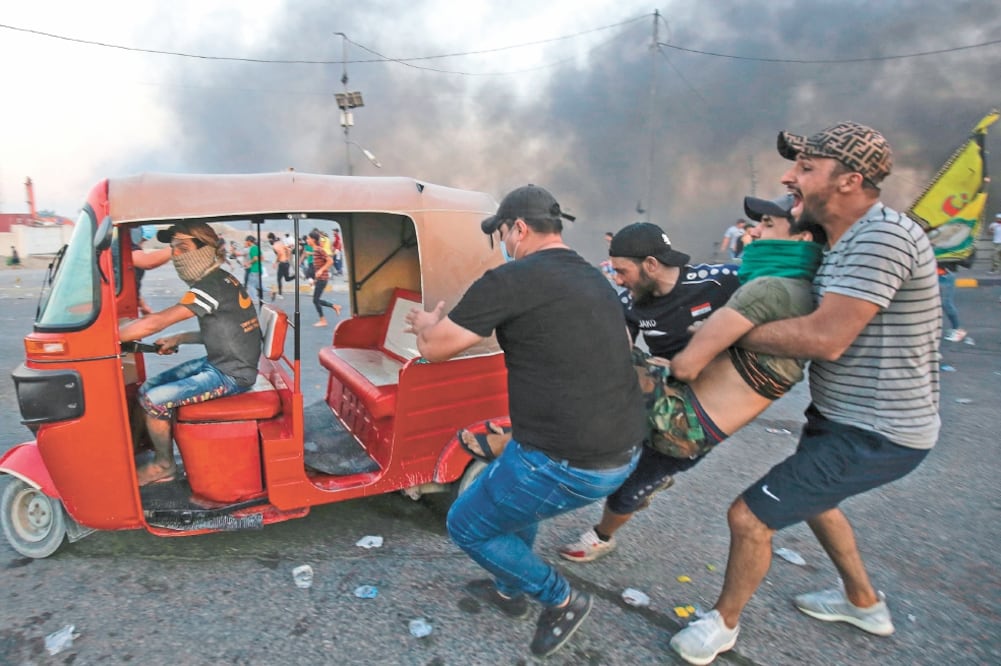 Manifestantes iraquíes ayudan a un hombre herido durante las protestas contra el gobierno en Bagdad. Foto/AHMAD AL-RUBAYE. AFP