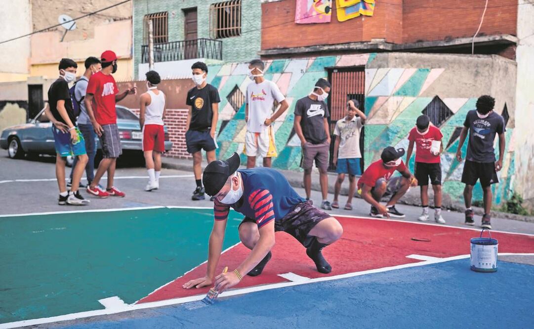 Jóvenes venezolanos pintan una cancha, como parte de un programa de recuperación en una zona violenta de Caracas. Foto: EFE.