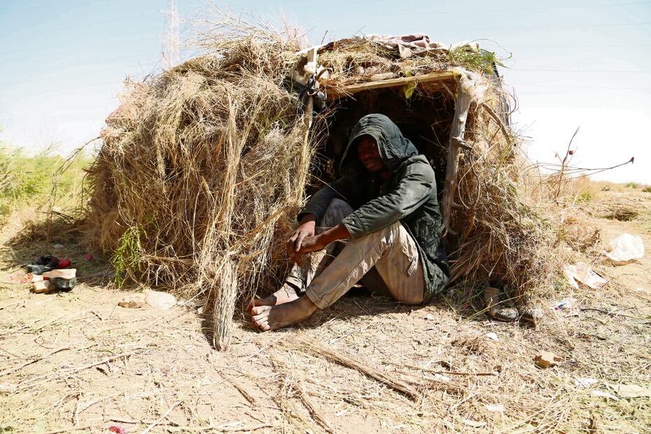Un hombre espera, mientras los migrantes se reúnen en una zona desértica en el lado libio de la frontera entre Túnez y Libia. Foto: Yousef Murad / AP