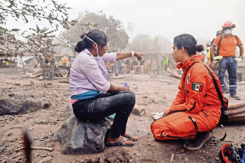 Eufemia García, de 48 años, quien perdió a 50 miembros de su familia en la erupción del Volcán de Fuego, con una integrante de los Topos de México (CARLOS JASSO. REUTERS)
