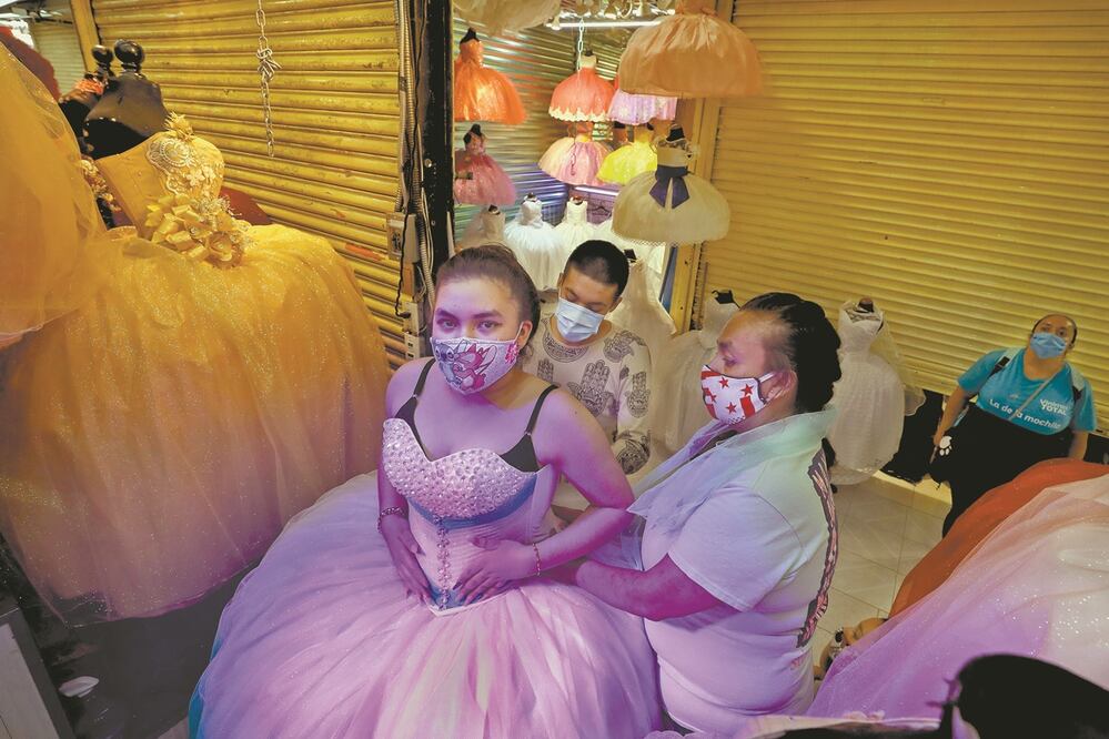Vendedores ayudan a Ximena a probarse vestidos. Tiene la esperanza de que cuando sea la fiesta hayan bajado los contagios y sus amigos puedan asistir. Fotos: DIEGO SIMÓN SÁNCHEZ