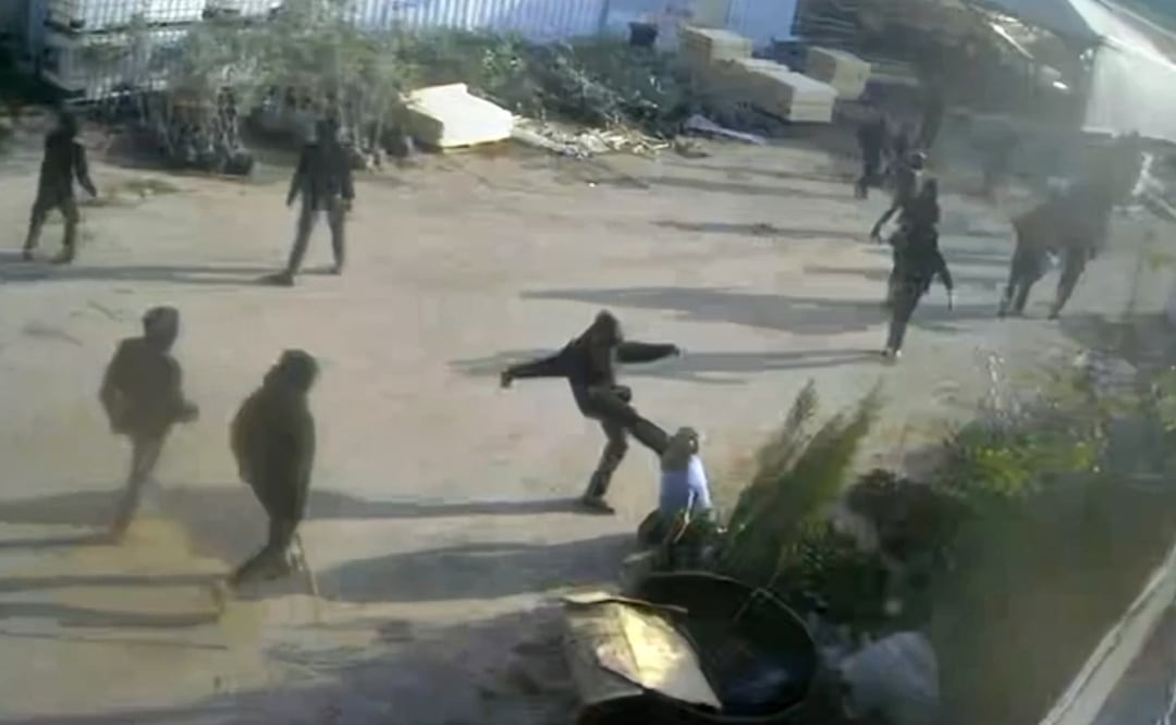 En esta imagen, tomada de una grabación de seguridad realizada el 8 de enero de 2026, hombres vestidos de negro y con los rostros ocultos --uno de ellos pateando a un hombre en el piso-- atacan un vivero de plantas en Deir Sharaf, en la Cisjordania ocupada.  Foto: AP