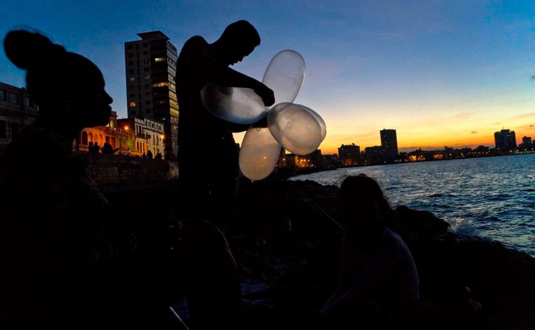 El mecánico Junio Torres López infla varios condones para su sedal que mantengan alta la carnada en el agua y aumentar la resistencia de la línea contra el peso de peces pesados. Fotografía de AP