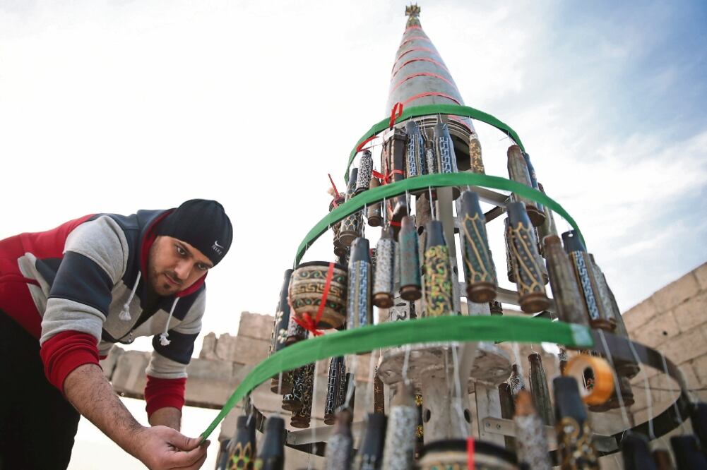 Akram Abu al-Foz decoraba ayer un árbol de Navidad con proyectiles vacíos que pintó, en la ciudad rebelde de Douma, al este de Damasco, la capital siria (BASAM KHABIEH. REUTERS)