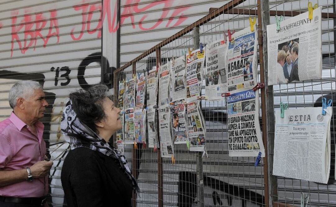 Dos ciudadanos leen las portadas de los diarios en un quiosco en el centro de Atenas.(Foto: EFE)