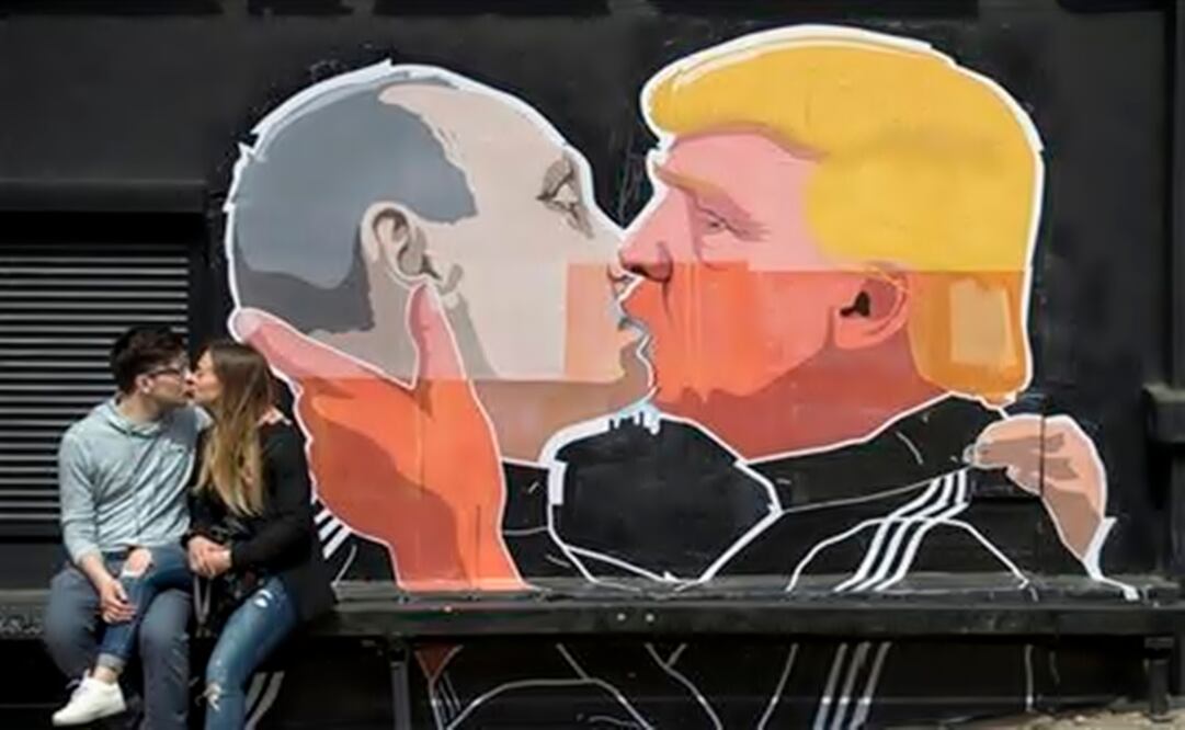   A couple kisses in front of graffiti depicting Putin and Trump, on the walls of a bar in Vilnius. (Photo: AP)
