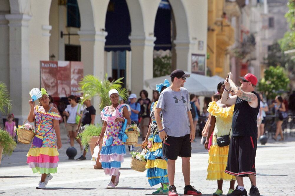 Turistas se toman fotos en una plaza de La Habana Vieja. Cuba tiene proyectos para ampliar puertos, aeropuertos y plazas hoteleras (ERNESTO MASTRASCUSA. EFE)