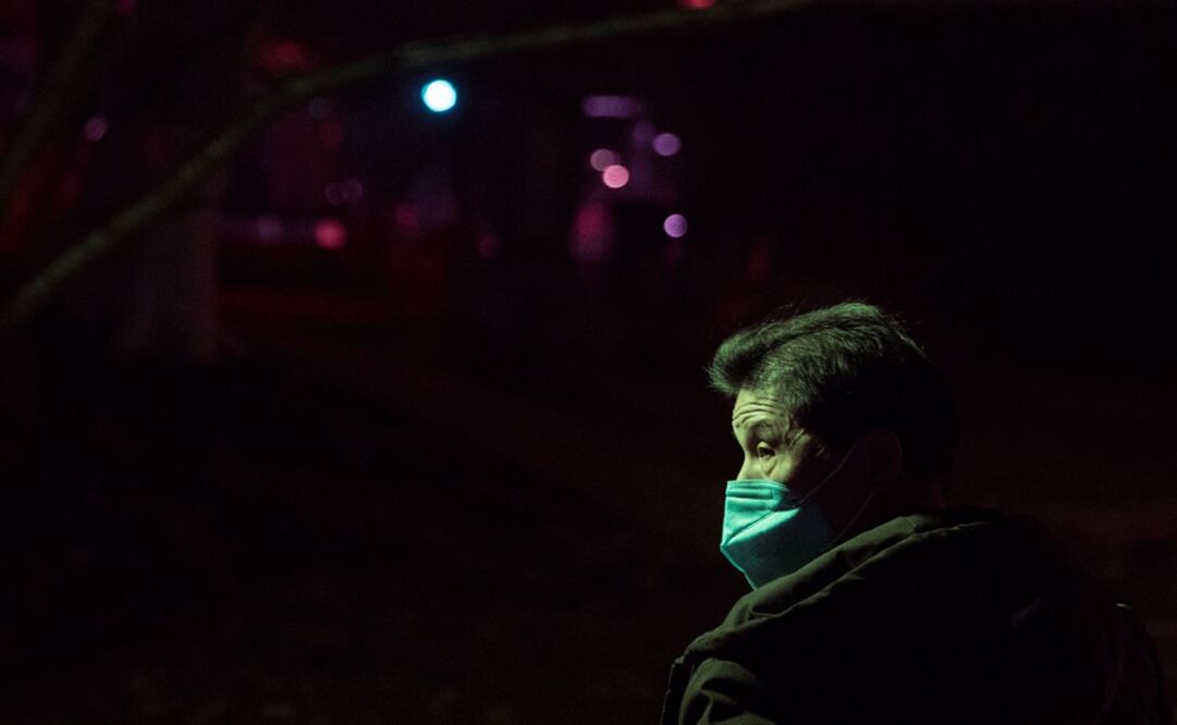 A man wearing a face mask walks in a park at night in Jiujiang, Jiangxi province, China - Photo: Thomas Peter/REUTERS