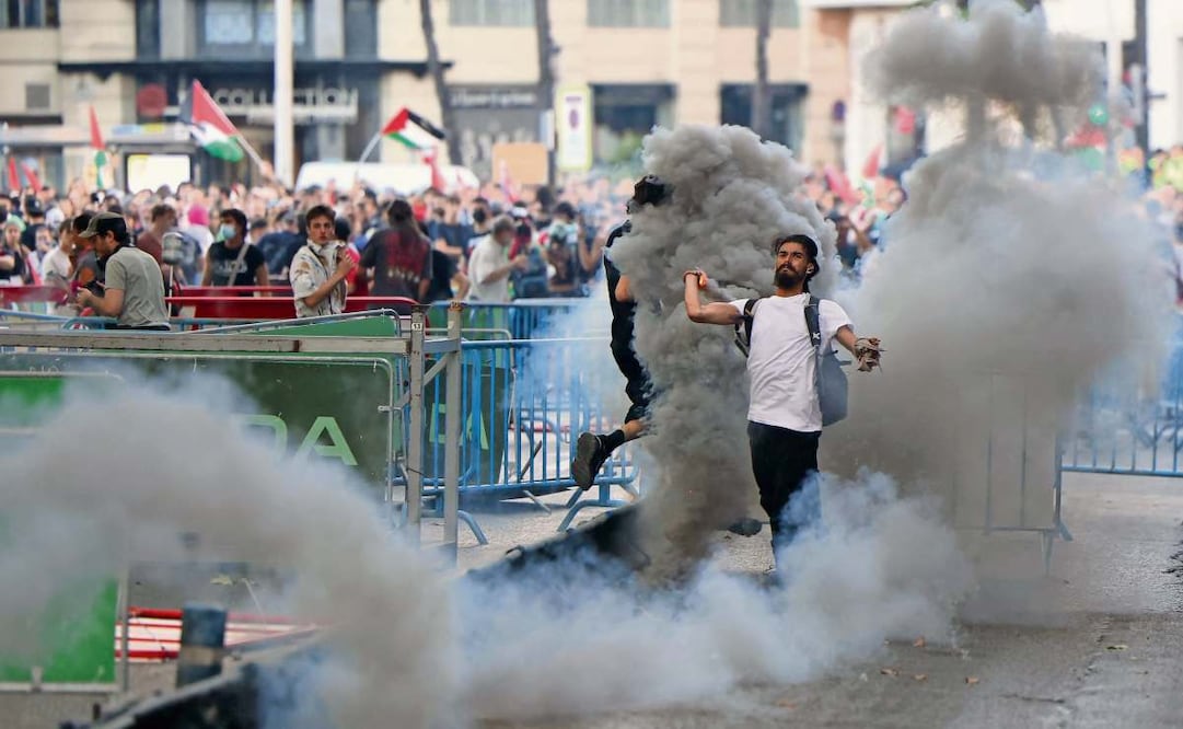 Un hombre lanza una lata de gas lacrimógeno a la policía, en medio de las protestas que obligaron a suspender la última etapa de la Vuelta ciclista en Madrid. Foto: Thomas Coex / AFP