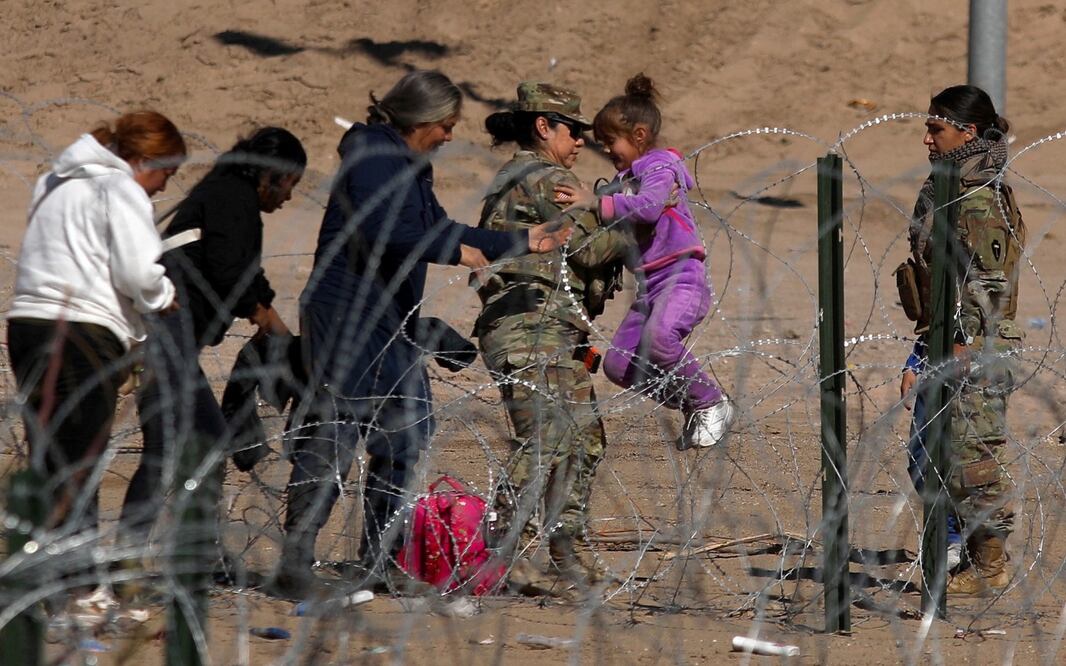 Un agente de la Guardia Nacional de Texas lleva a una niña migrante sobre una valla de púas en las orillas del Río Grande en El Paso, Texas. Foto: AFP