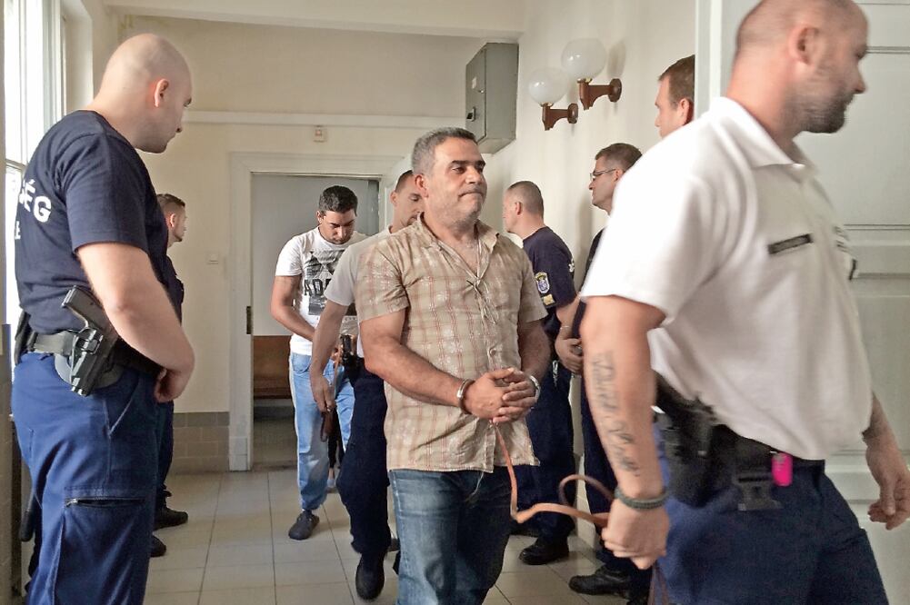 Dos de los acusados de traficar a los 71 migrantes cuyos cadáveres fueron encontrados el jueves en Austria, son trasladados a la corte en Hungría, país donde fueron detenidos y se les dictó prisión preventiva ayer (PABLO GORONDIL. AP)