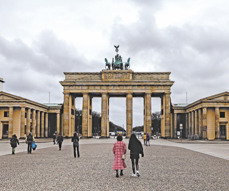Turistas, cerca de la Puerta de Brandenburgo, en Alemania, donde la mayoría de los comercios cerrarán y los oficios religiosos se cancelarán del 1 al 5 de abril. Foto: Filip Singer/ EFE.