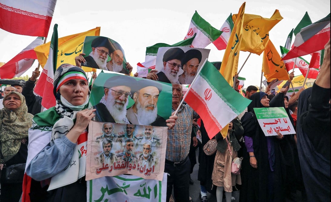 Una mujer iraní sostiene un cartel con los retratos del líder supremo iraní, el ayatolá Alí Jamenei y del difunto líder supremo, el ayatolá Ruhollah Jomeini, mientras la gente celebra el alto el fuego entre Irán e Israel en la plaza Enghlab de Teherán, el 24 de junio de 2025. Foto: AFP