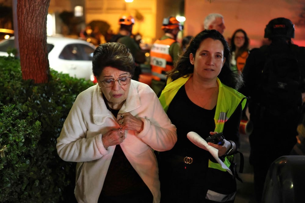 Una socorrista israelí evacuó a una civil del lugar donde, según informes, un proyectil impactó una casa en Shoham, en el centro de Israel, cerca de Tel Aviv. Foto: AFP