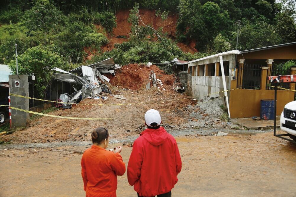 Afectados. Rescatistas miran el área donde murió una pareja aplastada en su casa tras un deslave, en las afueras de Panamá (ARNULFO FRANCO. AP)
