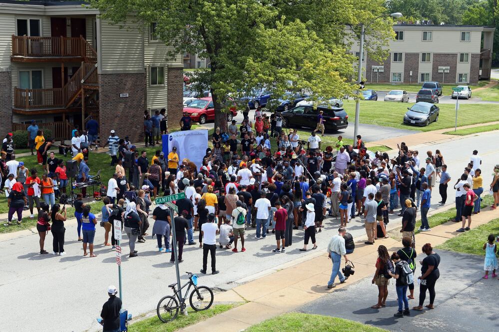 La familia de Michael Brown es acompañada por un grupo de personas durante un minuto de silencio en una ceremonia previa a una manifestación  (Foto: AP)