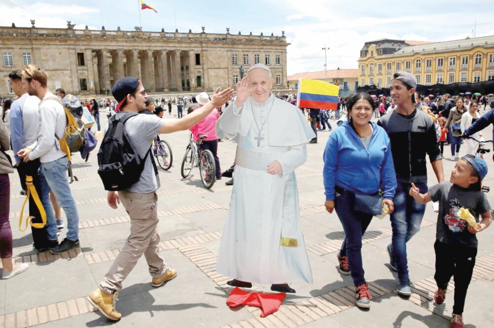 Un joven saluda a una figura de cartón del papa Francisco colocada afuera del palacio de Nariño, en el centro histórico de la ciudad de Bogotá (HENRY ROMERO. REUTERS)