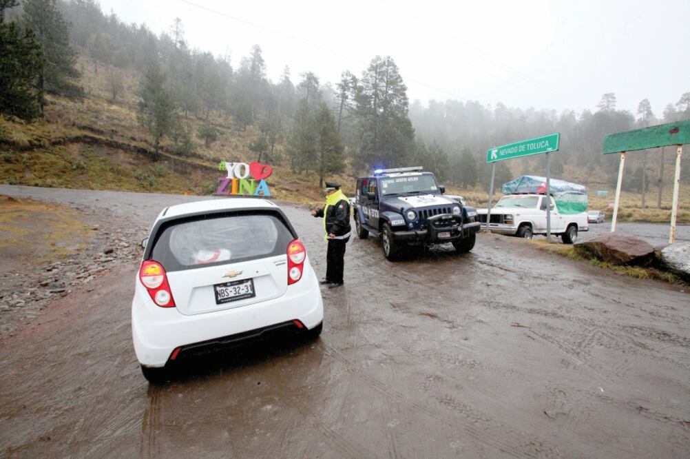 Autoridades explicaban a los paseantes que por el mal tiempo el camino no era seguro ni para subir caminando, pues la lluvia se solidificó por las bajas temperaturas creando una capa de hielo que dificultaba el tránsito por la zona. (JORGE ALVARADO. EL U)