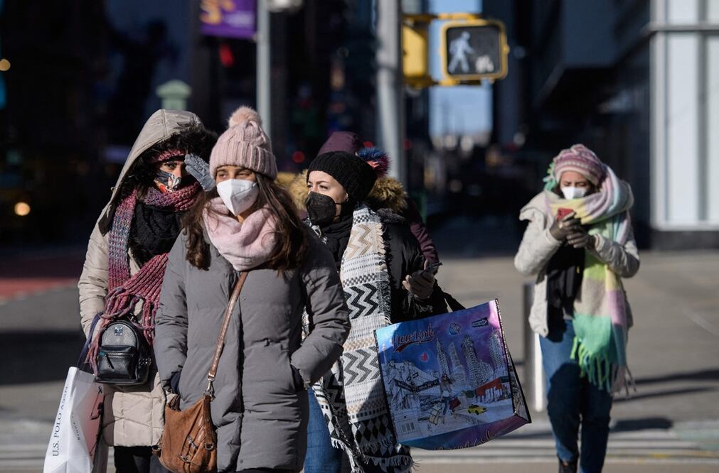 Transeúntes se protegen del frío y del Covid-19, durante la época invernal. Foto: AFP / Angela Weiss