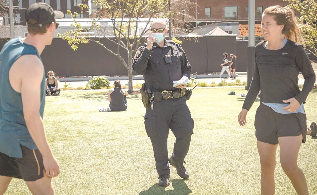 Un policía da cubrebocas en Domino Park, Brooklyn, Nueva York, donde mil oficiales fueron desplegados para que se cumplan las normas de salud. Foto: GARY HE. EFE