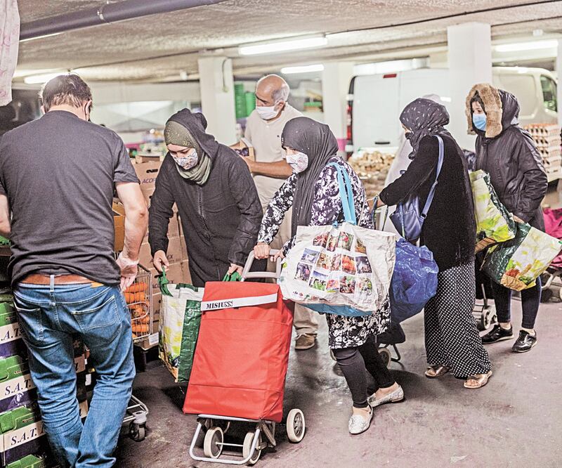 Personas recogen comida donada por voluntarios y por integrantes de los Siervos de Jesús y María, en Madrid. Foto: BERNAT ARMANGUE. AP