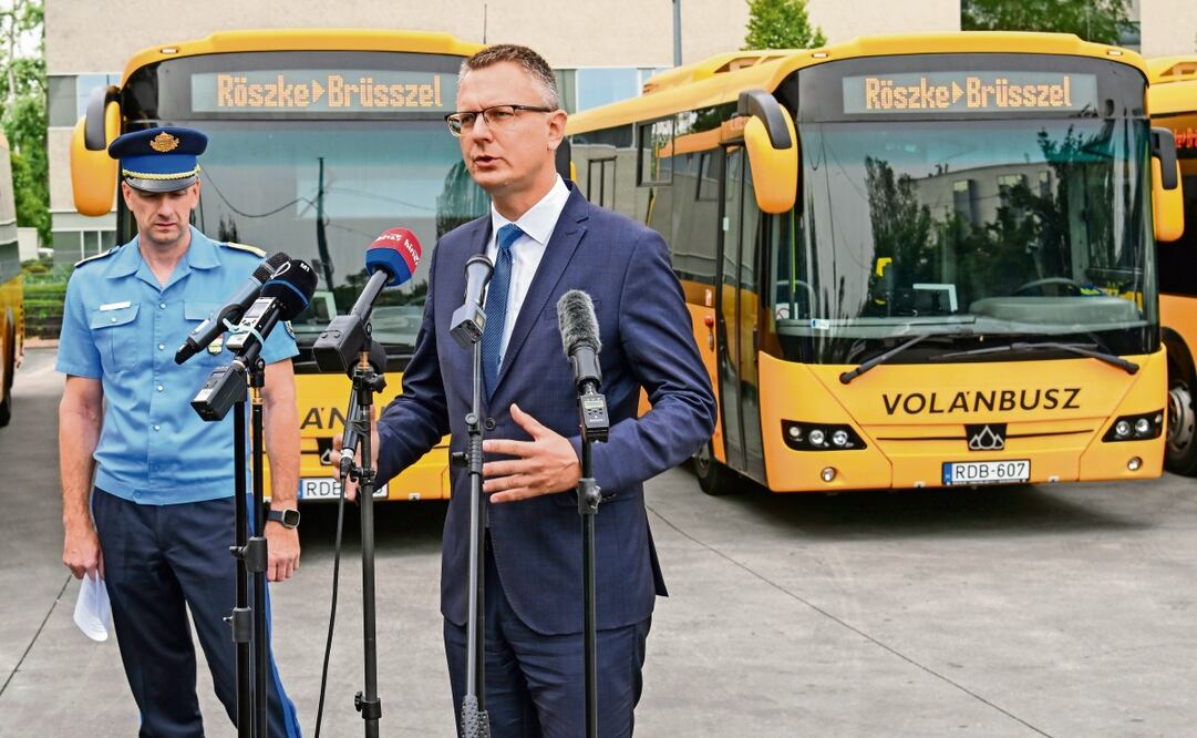 El secretario del Estado de Hungría, Bence Rétvári, a la derecha, y el policía Janos Kuczik, en la estación de autobuses de Nepliget, Budapest, con el telón de fondo de una fila de camiones de pasajeros que decían “Röszke-Bruselas”, una ruta que llevaría a los inmigrantes desde la frontera sur de Hungría con Serbia hasta la sede de la UE en Bélgica.Foto: Patricia de Melo Moreira / AFP