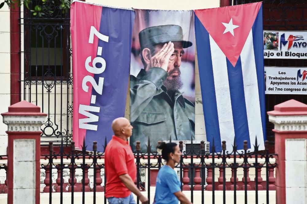 Dos personas caminan en la Habana, junto a un lienzo con la imagen del líder de la Revolución Fidel Castro, a pocos días de que se dé el cambio presidencial en la isla. (ALEJANDRO ERNESTO. EFE)